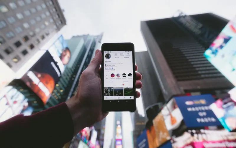 Hand holding a phone showing a social feed